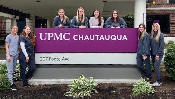 8 students standing in front of a sign that says UPMC Chautauqua.